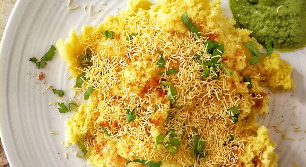 Steamed Surti Locho served with sev, onions, and coriander